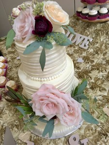Photo of a three tier wedding cake decorated with pink and purple roses